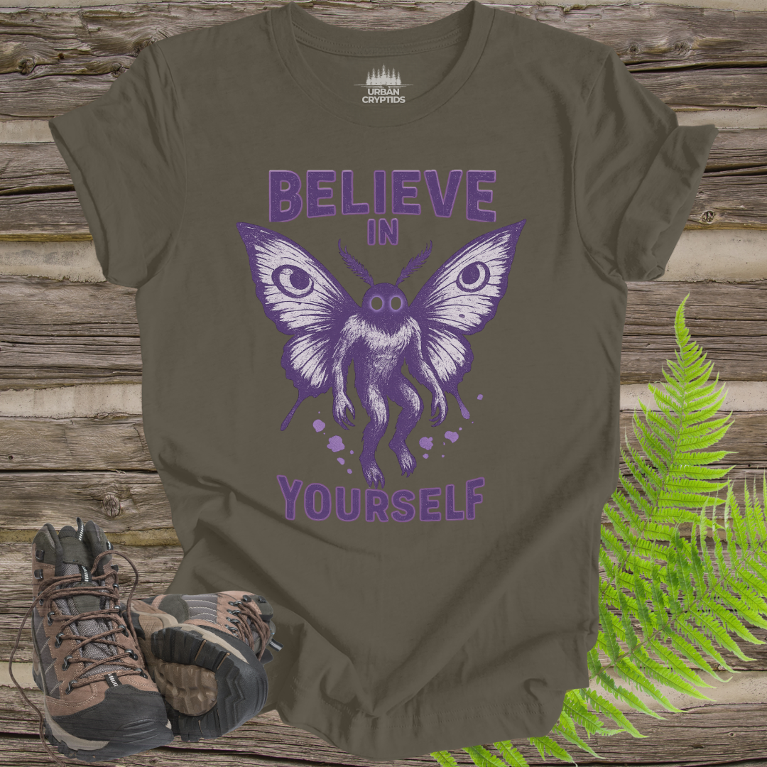 Brown t-shirt with purple butterfly graphic and 'Believe in Yourself' text on a wooden surface with boots and ferns.