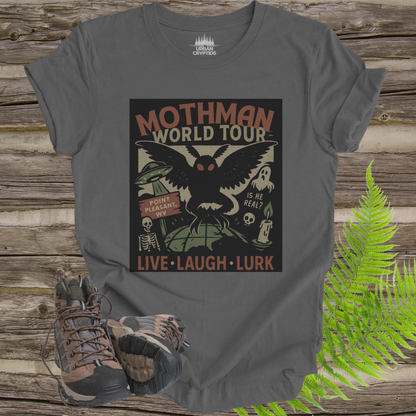 Gray t-shirt with Mothman graphic design on a wooden surface with hiking boots and ferns.