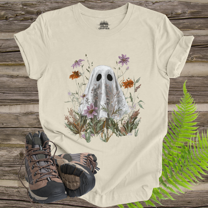 Beige t-shirt with ghost and floral design on a wooden surface with hiking boots and ferns.